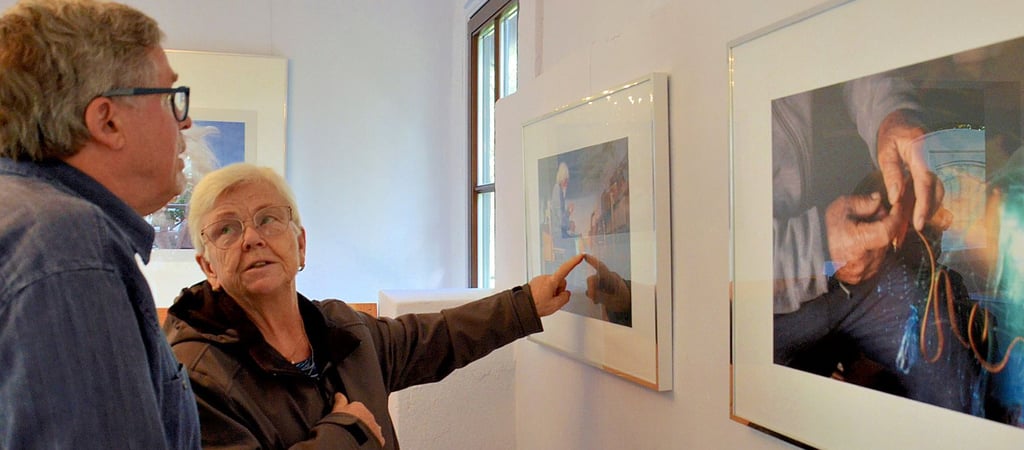 Sigrid Becker im Gespräch mit Galerist Joachim Springer. Beide sehen sich Fotos einer Sizilienreise von Sabine Otte an.