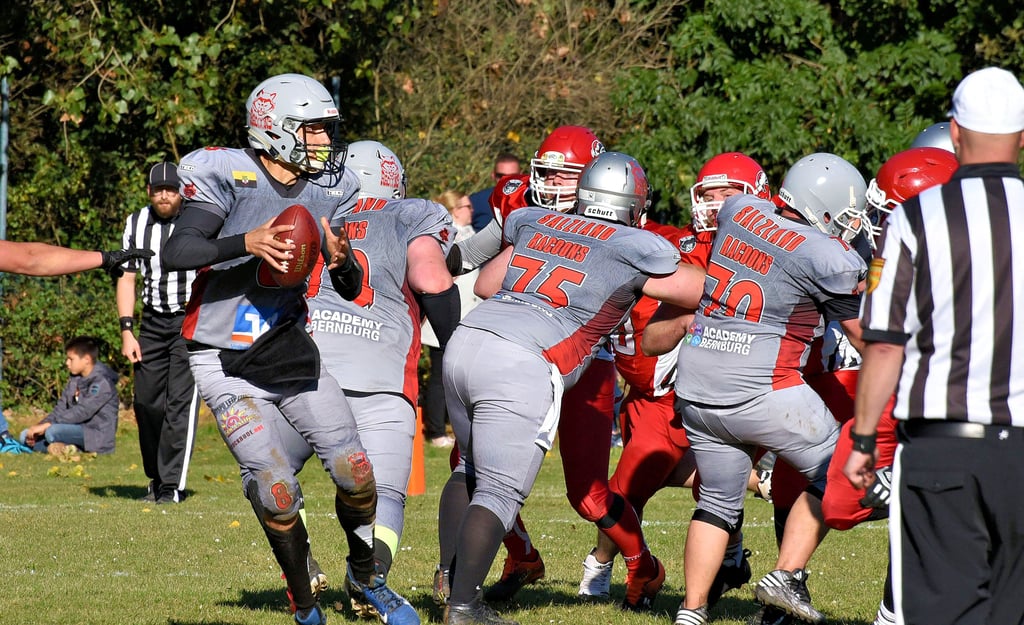 Quarterback Johannes Ruprecht versucht mit dem Football Raum zu gewinnen, während ihm der Rücken frei gehalten wird.