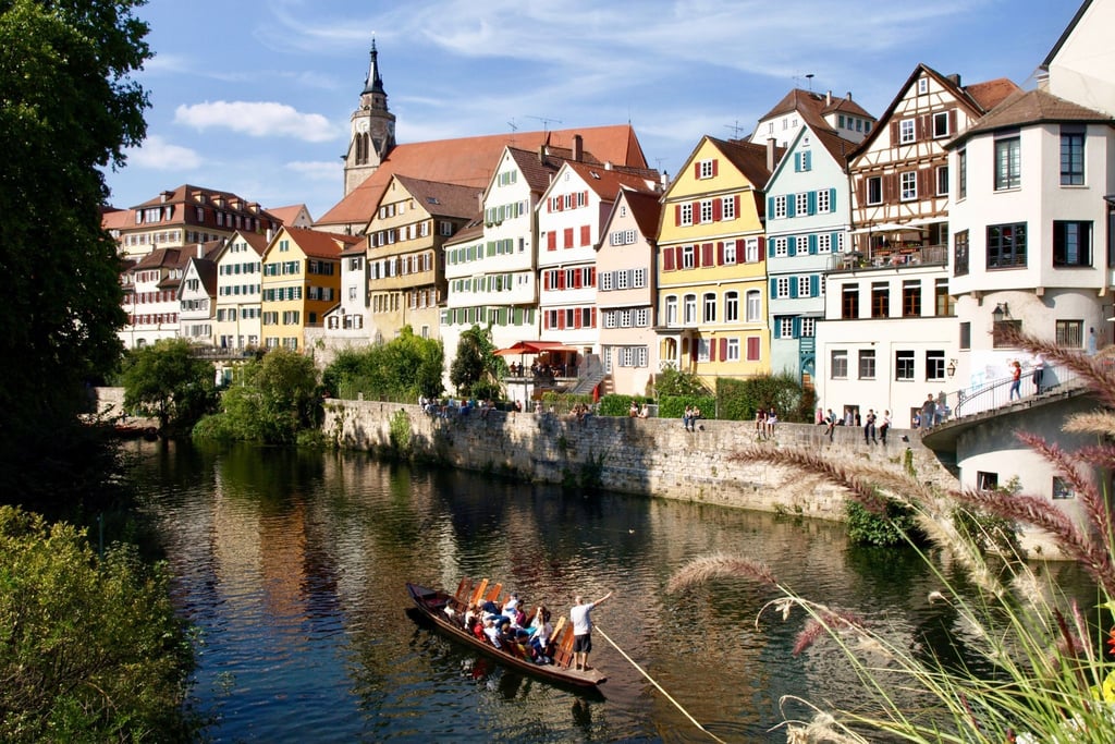 Der Bootsführer im Stocherkahn erklärt Touristen die Neckarfront in Tübingen.