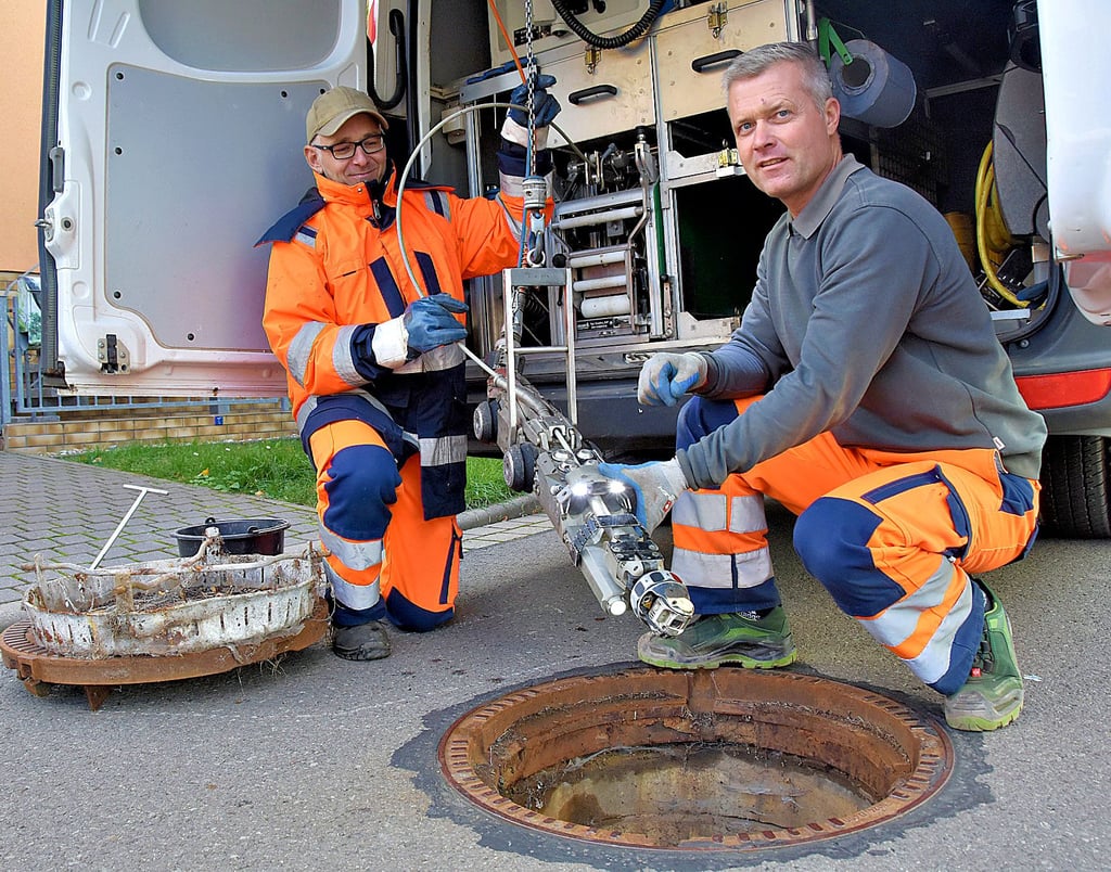 Der Abwasserverband „Untere Ohre“ setzt auf modernste Technik, um das Abwassersystem zu kontrollieren. René Olbrich (vorn) und Ronny Kleinecke lassen die fahrbare Kamera in den Kanalschacht der Morgenstraße in Althaldensleben herab. Die Kamera liefert Bilder vom Untergrund.