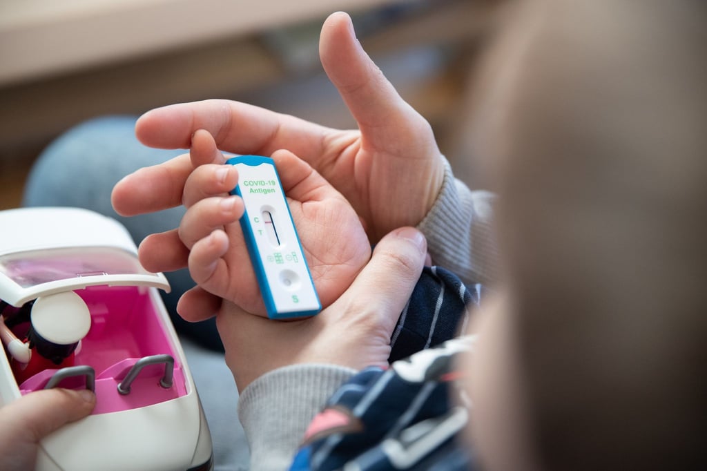 Ein Kita-Kind und seine Mutter warten daheim auf das Ergebnis eines Corona-Selbsttests.