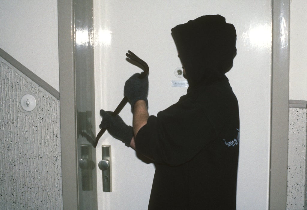 Ein Einbrecher dringt in eine Wohnung ein.