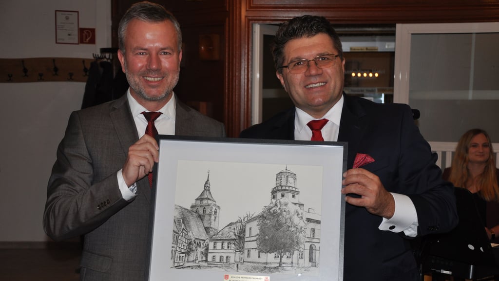 20 Jahre Osterburg und Wielun: Ein polnischer Künstler zeichnete die Rathäuser aus diesem Anlass einfach direkt nebeneinander. Der Osterburger Bürgermeister Nico Schulz (links) war beeindruckt von der Collage, die ihm sein Wieluner Amtskollege Pawel Okrasa überreichte.