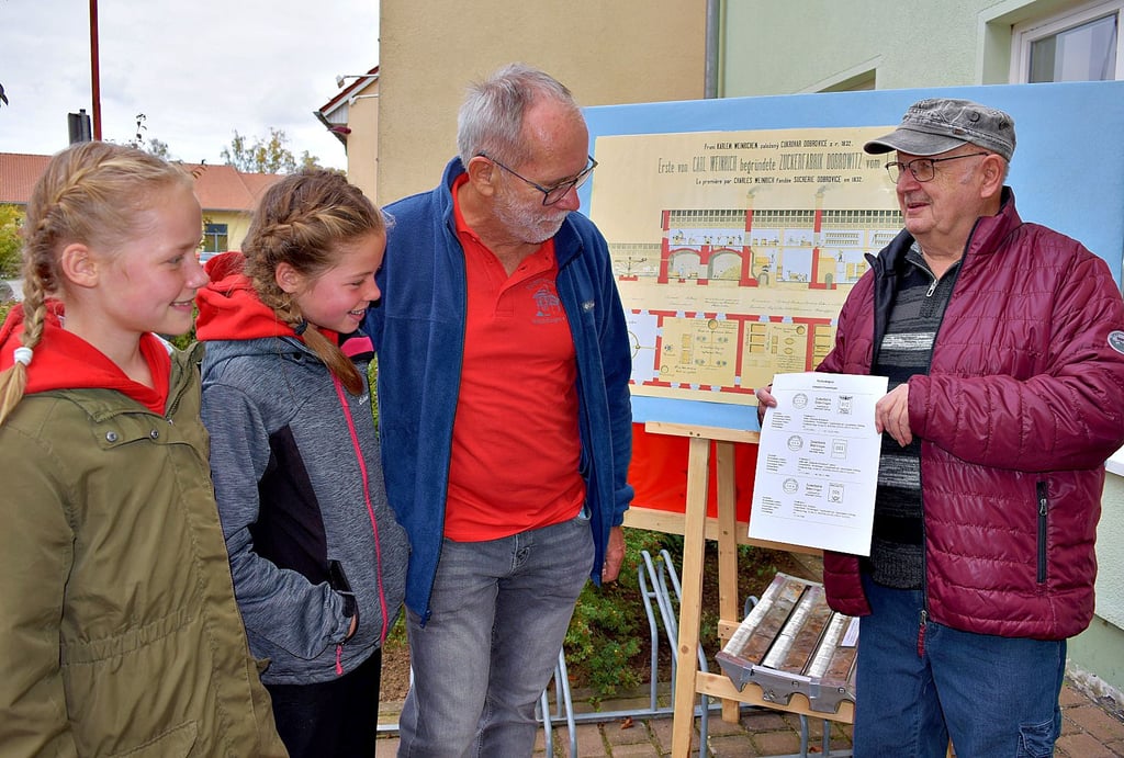 Briefmarkensammler Klaus Hirschfeld (r.) überrascht Bernd Hoffmann mit Kopien von Absenderfreistempeln der Zuckerfabrik Weferlingen. Auch Bernd Hoffmanns Enkelinnen Catharina (l.) und Alexis sehen sich die Stempel an.