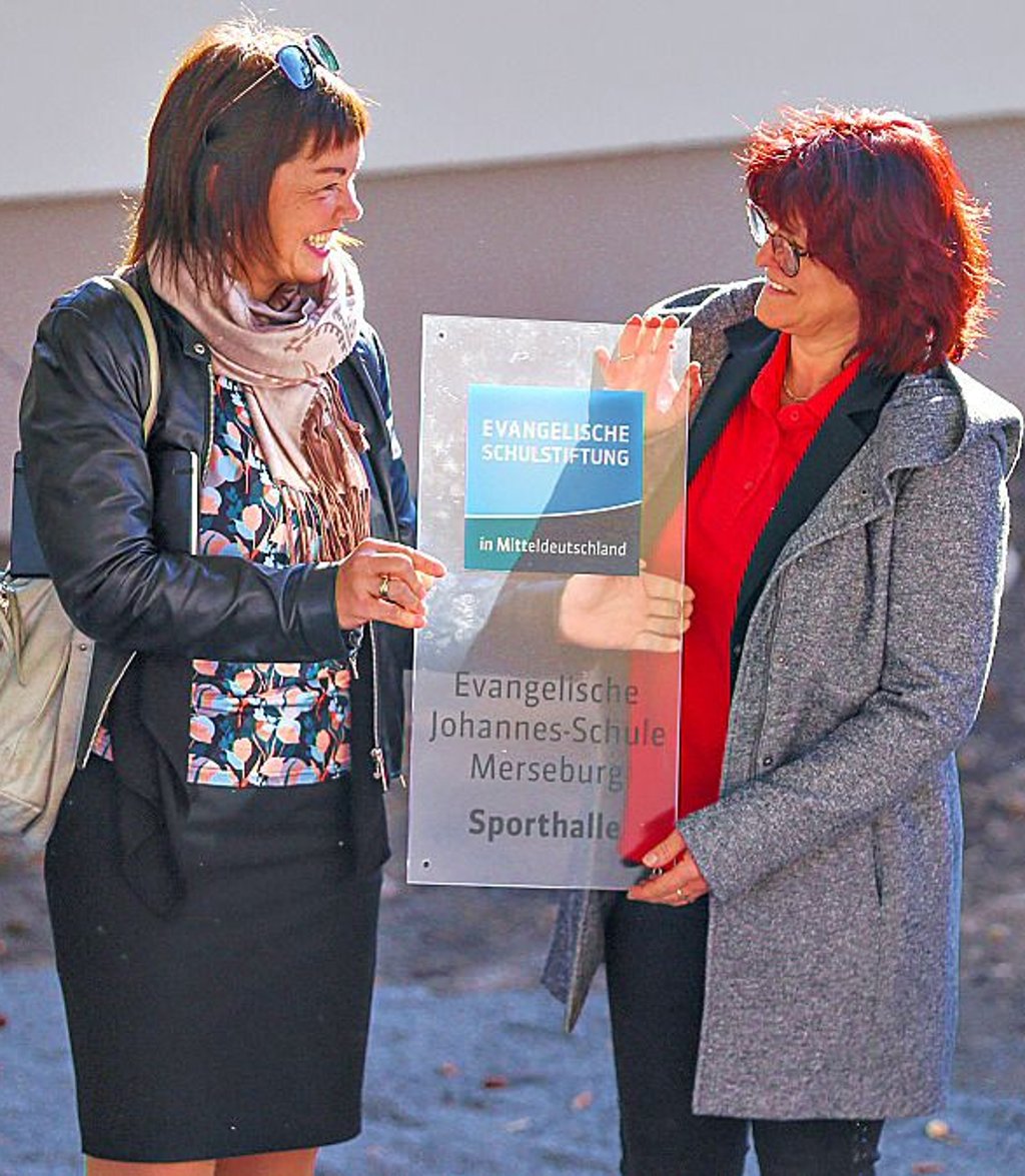 Katrin Schumak (l.) überreicht Peggy Grünke (r.) das neue Schild.