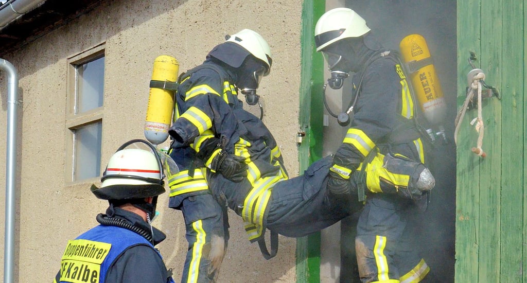 Finale Feuerwehrübung zum Abschluss der Truppführerausbildung: Einsatzkräfte bringen eine vermisste Person aus der Lagerhalle ins Freie.