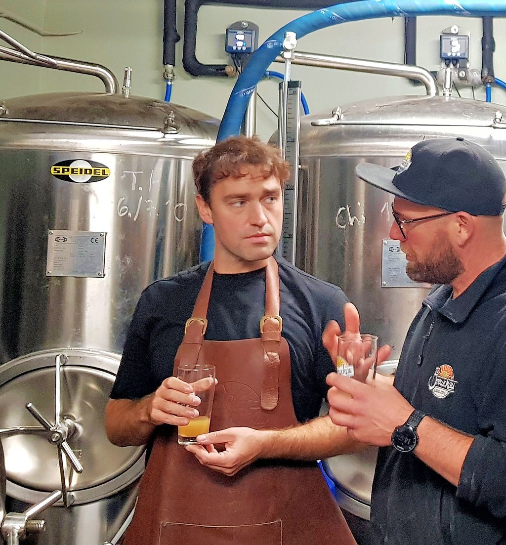 Der Magdeburger Brauereichef Robert Kellermann (r.) weist Sänger und Praktikant Benoby in die Kunst des Bierbrauens ein.