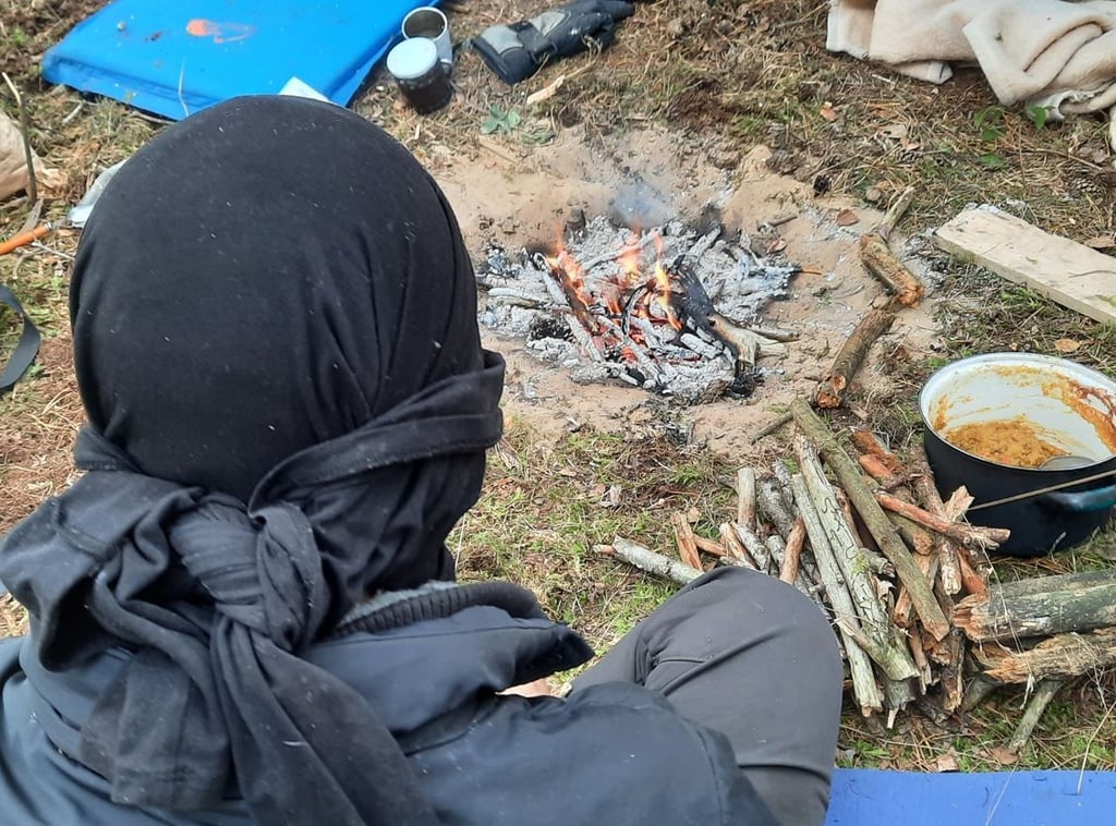 Ein Aktivist sitzt an einem Lagerfeuer im Camp bei Storbeck.