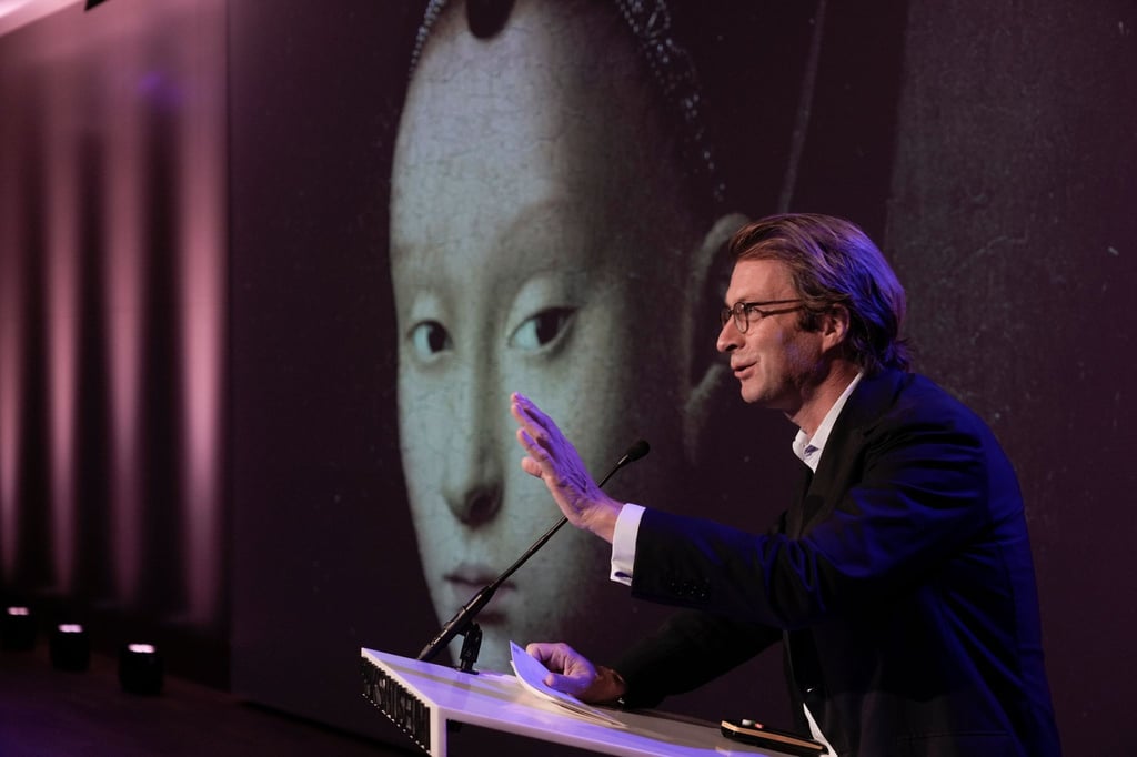 Taco Dibbits, Generaldirektor des Rijksmuseums, spricht über die Ausstellung "Remember Me" (dt: Vergiss mich nicht), während das Porträt einer jungen Frau von Petrus Christus auf die Leinwand projiziert wird