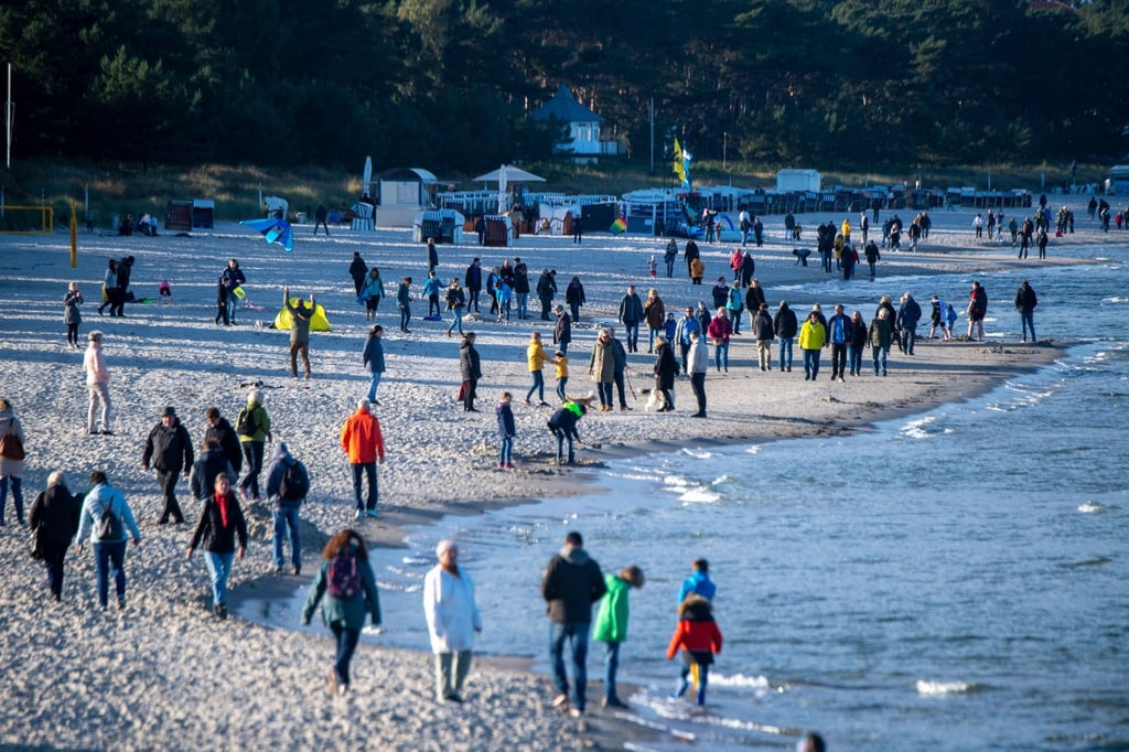 Touristen am Strand vor der Seebrücke im Ostseebad Binz.