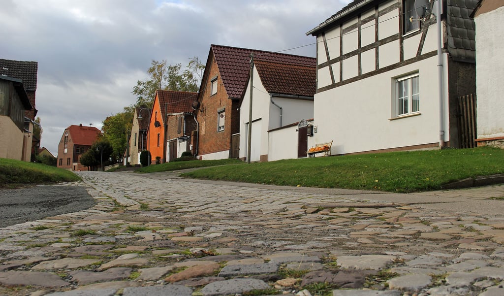 Ein Teil der Schulstraße in Druxberge, die bislang ein Flickenteppich aus altem Kopfsteinpflaster, Betonbanketten und geteerten Abschnitten ist. Die Ertüchtigung soll im Früjahr 2022 endlich erfolgen.