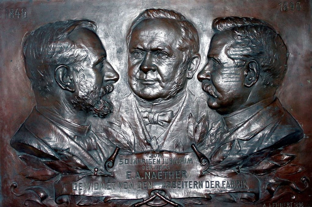 Das ist die Bronzeplatte mit den Reliefs von Ernst Albert Naether und seinen beiden Söhnen Albin und Richard.