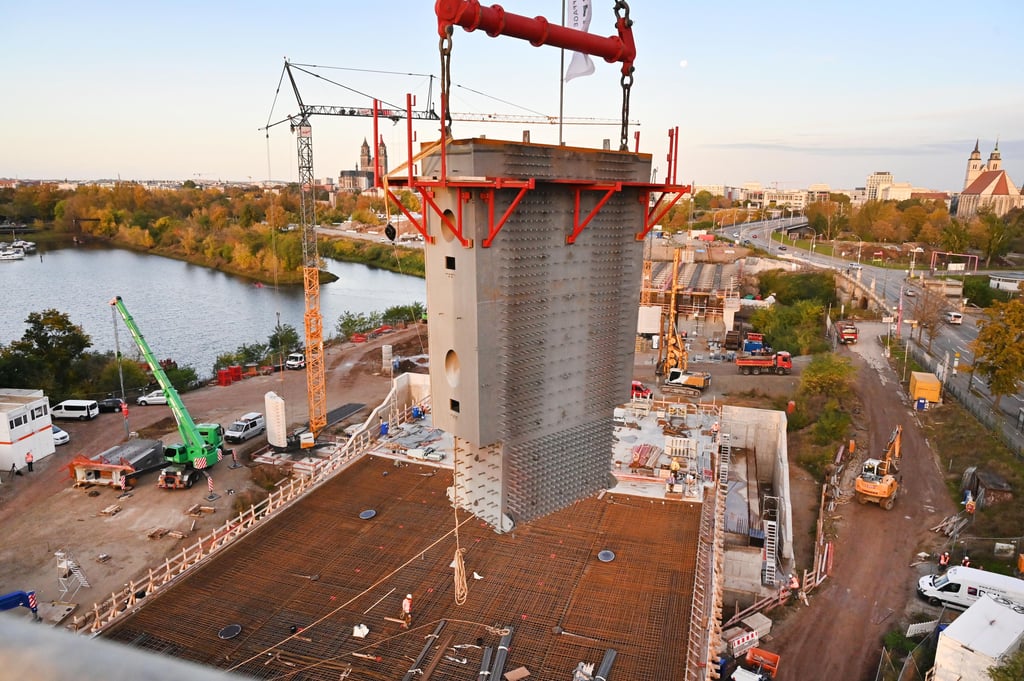 Die etwa 30 Tonnen schweren Stahlbauteile wurden am 22. Oktober 2021 mit Hilfe eines Spezialkrans mit einer Hubleistung von 750 Tonnen auf die etwa 50 Meter hohen Pylonbeine über die Alte Elbe in Magdeburg gehoben. Dabei handelt es sich um den ersten Teil der beiden Pylonköpfe. Die zweiten und gleichzeitig letzten Kopfteile – Stahlbauteile mit einem Gewicht von jeweils 70 Tonnen – werden voraussichtlich Anfang des kommenden Jahres aufgesetzt. Hier ein Blick aus 50 Meter Höhe auf die Baustelle