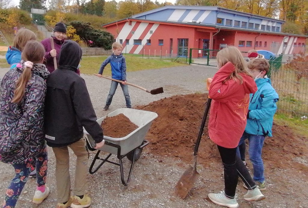 Gisa Fölsch vom Wildpflanzen-Verein im Harz pflanzt mit Benneckensteiner Grundschülern weitere Bäume für den Ewilpa.