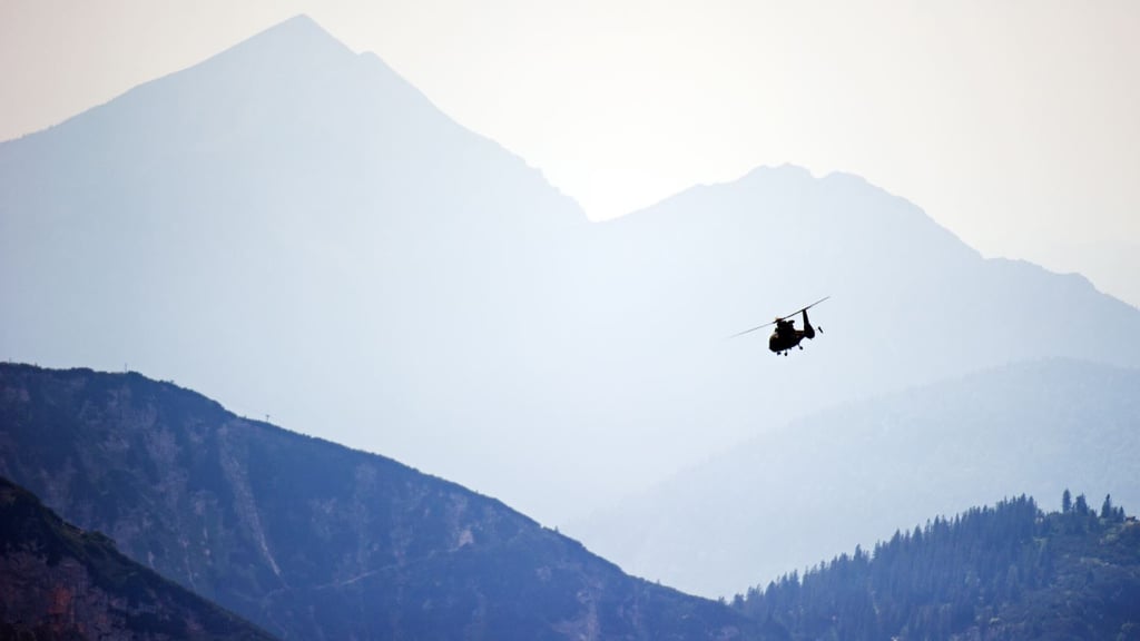 Ein Helikopter der Bergrettung kreist über einem Gebirge.