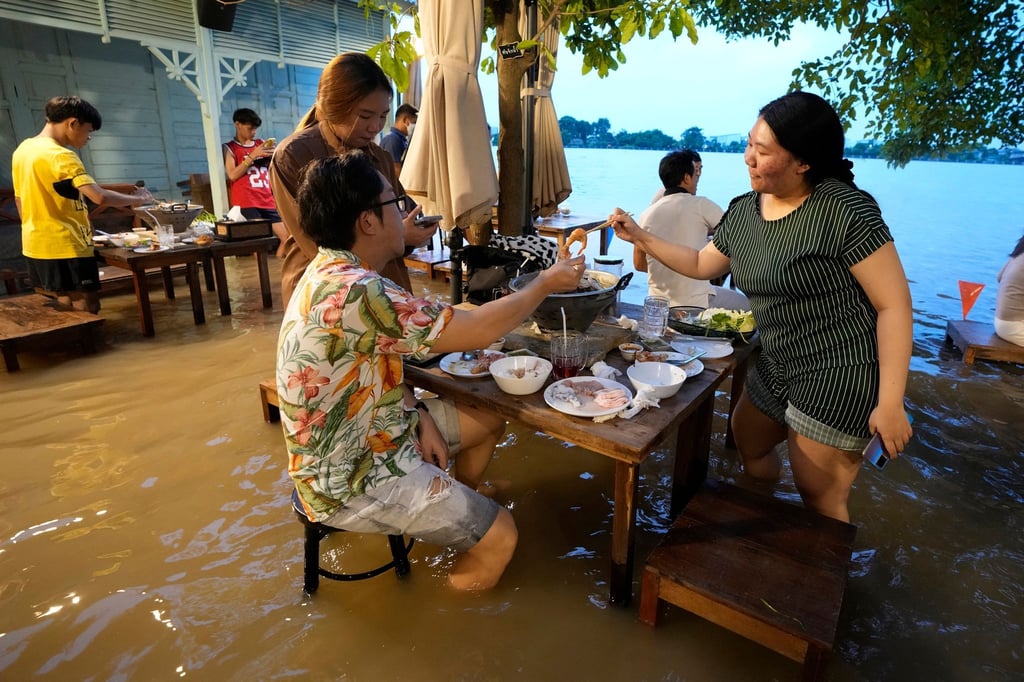 Menschen sitzen trotz des hohen Wasserstands im „Chaopraya Antique Café“. Das von der Flutkatastrophe betroffene Restaurant hat sich zu einem Hotspot entwickelt.