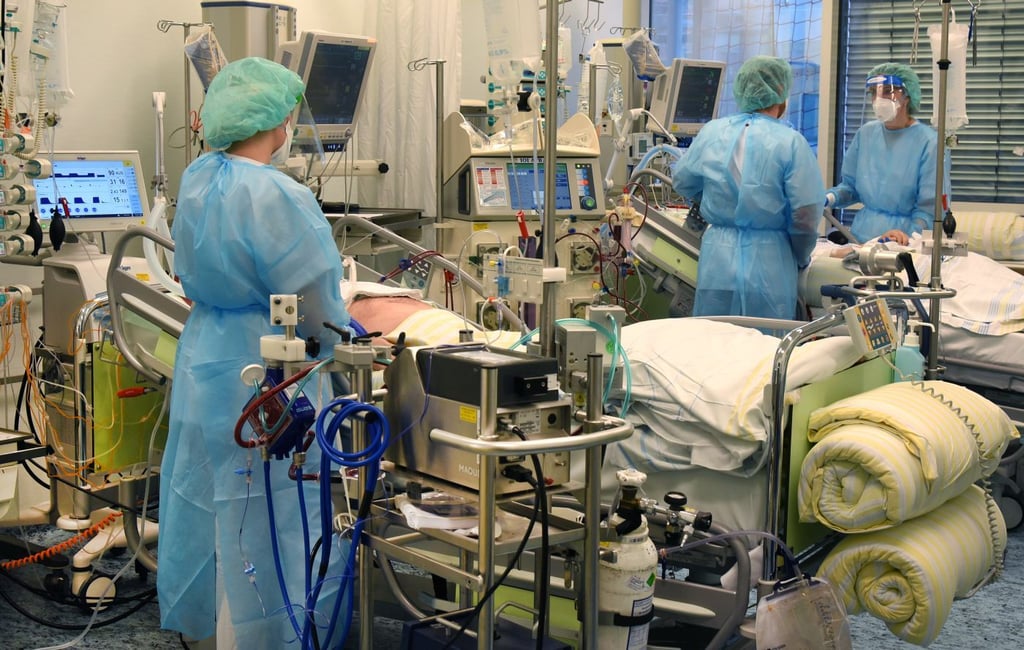 Auf der Covid-Station, einem Bereich der Operativen Intensivstation vom Universitätsklinikum Leipzig, stehen ein Arzt (2.v.r.) und zwei Schwestern an Betten von Patienten.