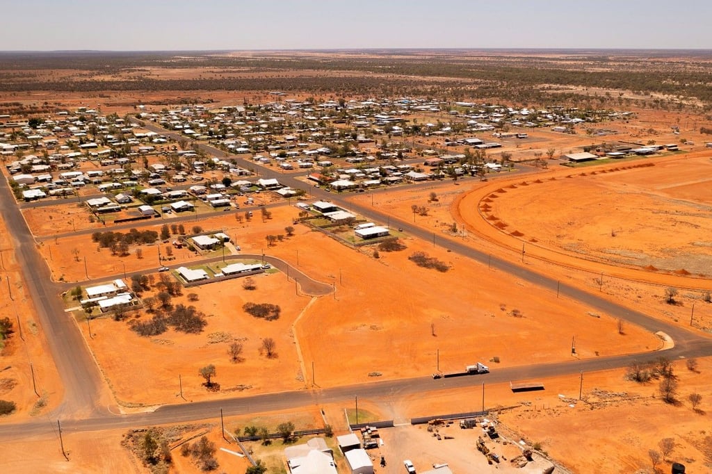 Das australische Outback-Dorf aus der Luft, umgeben von roter Erde und spärlicher Vegetation.
