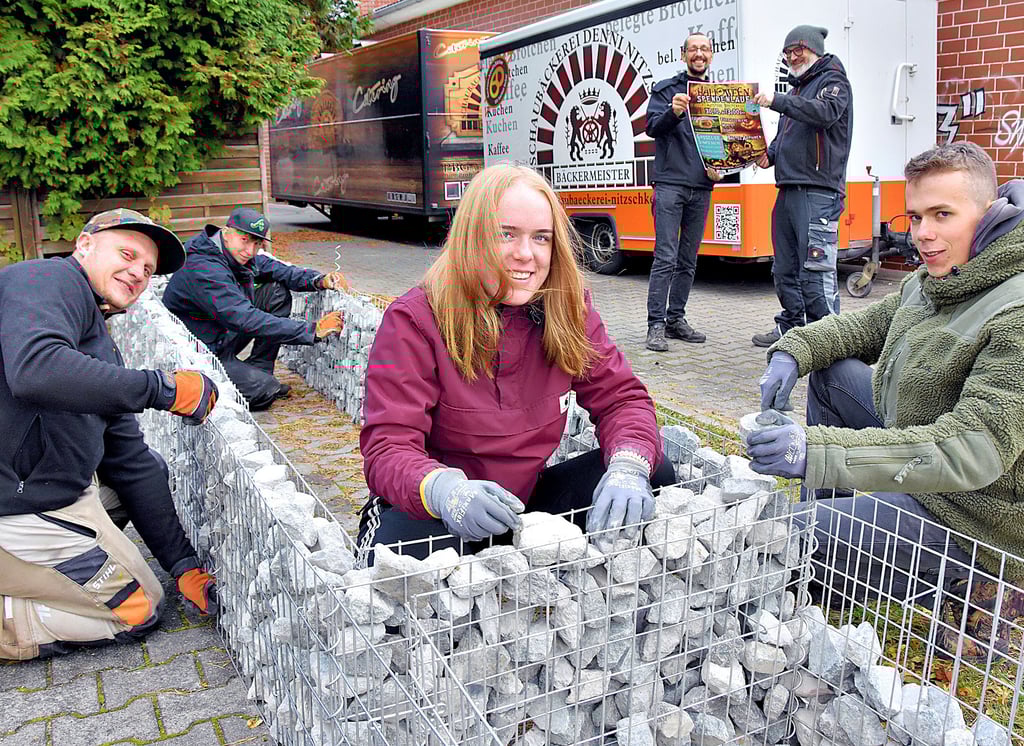 Emma Bär, Fabian Sprott (r.), Christoph Swoihze (l.) und Jakob Sarazet verteilen auf dem Parkplatz hinter dem Goldenen Löwen in Calvörde die Natursteine in der Gitterbegrenzung der neuen Hochbeete. Die Beete werden mit Obststräuchern bepflanzt.