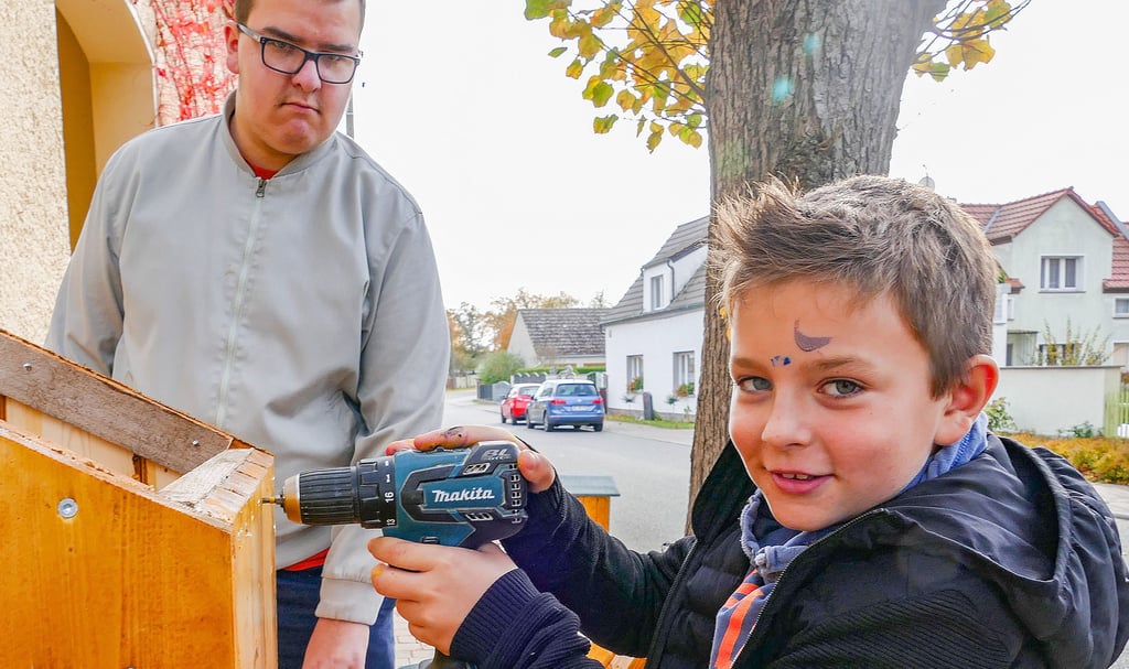 Lio Nowack schraubt unter Anleitung die neuen Hydrantenhäuser für Bethau zusammen. Der Neunjährige hatte den Antrag bei der Ev. Akademie eingereicht und damit das Projekt „Die Kinder verschönern die Hydrantenhäuser“ möglich gemacht.
