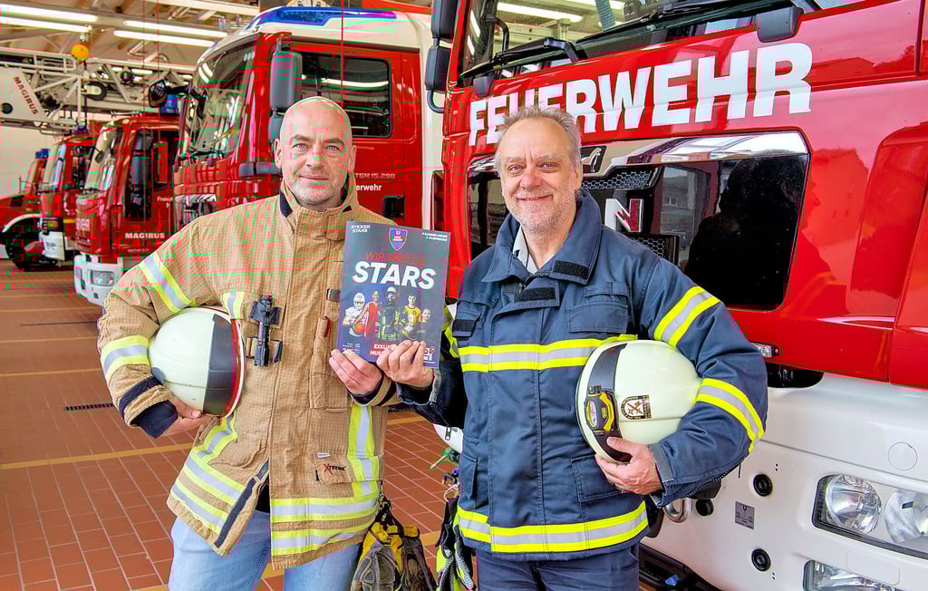 Stadtwehrleiter Christian Schirner und David Abram, stellvertretender Wehrleiter, zeigen ein Muster-Album. Das richtige nebst Sticker gibt es am kommenden Sonnabend am ersten Verkaufstag.