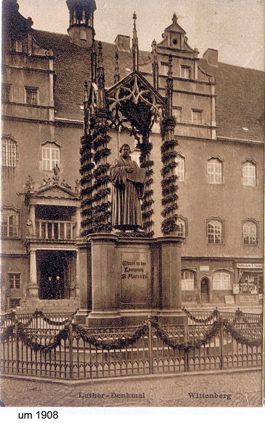 Lutherdenkmal auf Postkarte 1908: Hinter dem geschmückten Denkmal sind noch die Läden im Untergeschoss des Rathauses erkennbar.