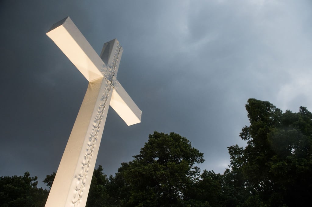Dunkle Wolken über einem Kreuz.