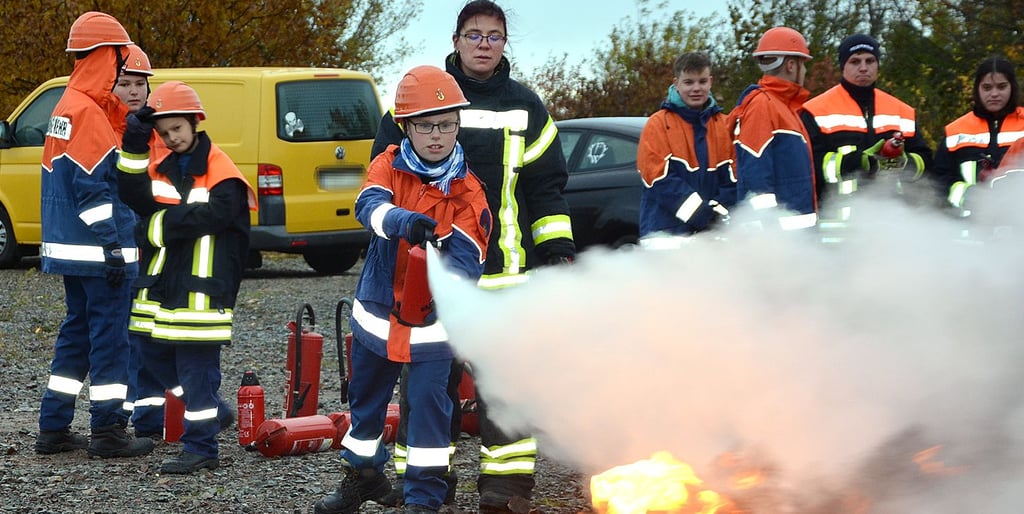 Moritz löscht das Feuer. Jugendwartin Kathleen Gerecke von der Freiwilligen Feuerwehr Wegeleben schaut ihm dabei über die Schulter.