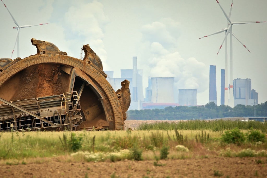 Der Schaufel eines Braunkohlebaggers baggert im Tagebau Garzeiler; im Hintergrund stehen eines der RWE-Kraftwerke und daneben Windräder. Während die Energiepreise steigen, will die COP26 in Glasgow sich dem Klimawandel stellen.