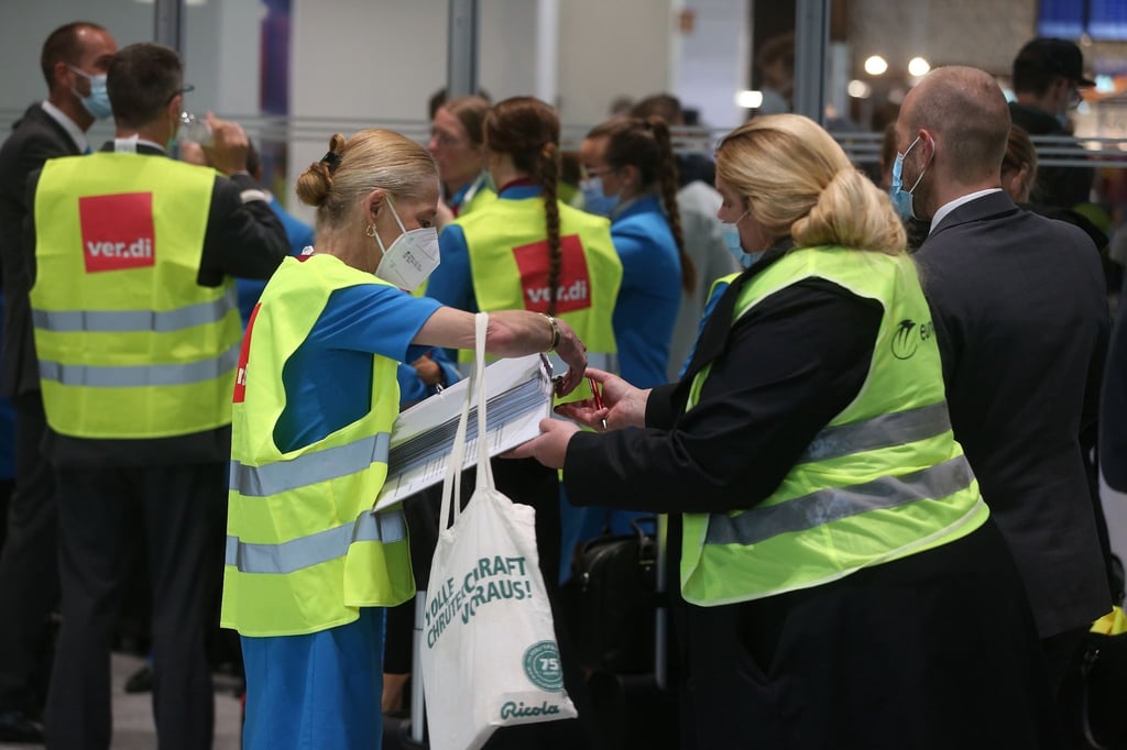 Personal der Eurowings steht beim Warnstreik mit verdi-Westen im Flughafen und trägt sich in Listen für Streikgeld ein.