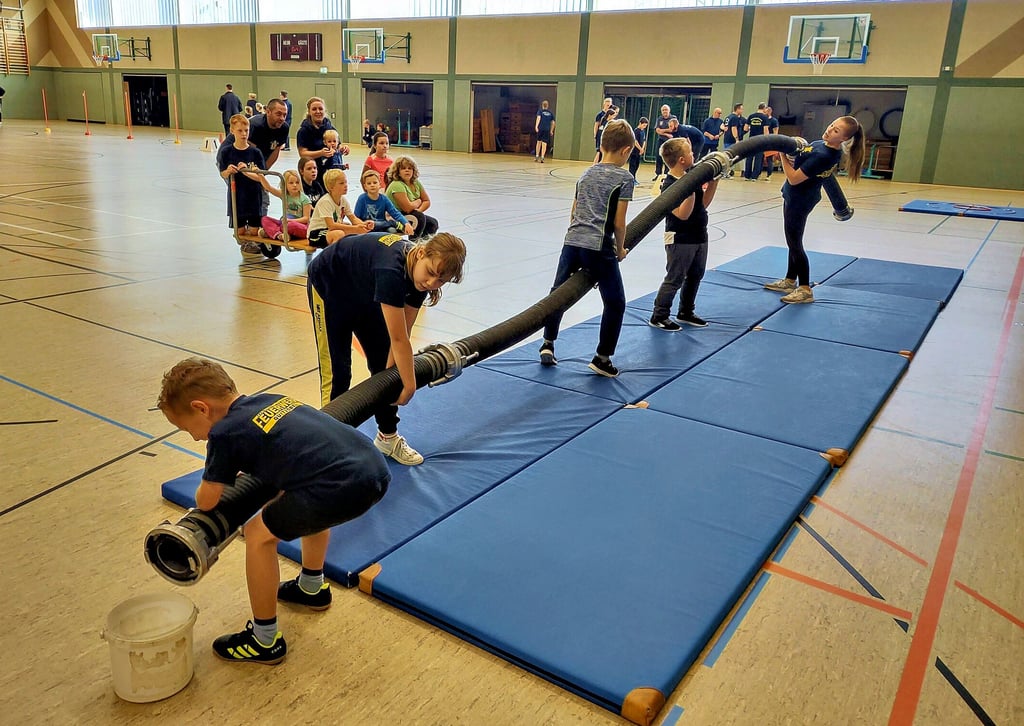 Das Team der Kinderwehr aus Quitzöbel hat fünf Sauglängen zusammengekuppelt. In den bereitgestellten Eimer muss nun nur noch ein kleiner Ball fallen, der ganz vorne in der ersten Sauglänge auf die Reise geschickt wird.