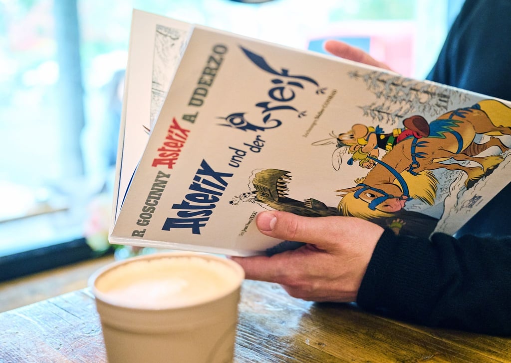 Ein Mann schaut in den neuen Asterix-Band "Asterix und der Greif".