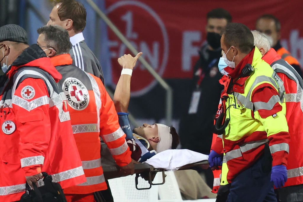 Der Nürnberger Tom Krauß (M) wird verletzt aus dem Stadion getragen, zeigt aber mit dem Daumen nach oben.