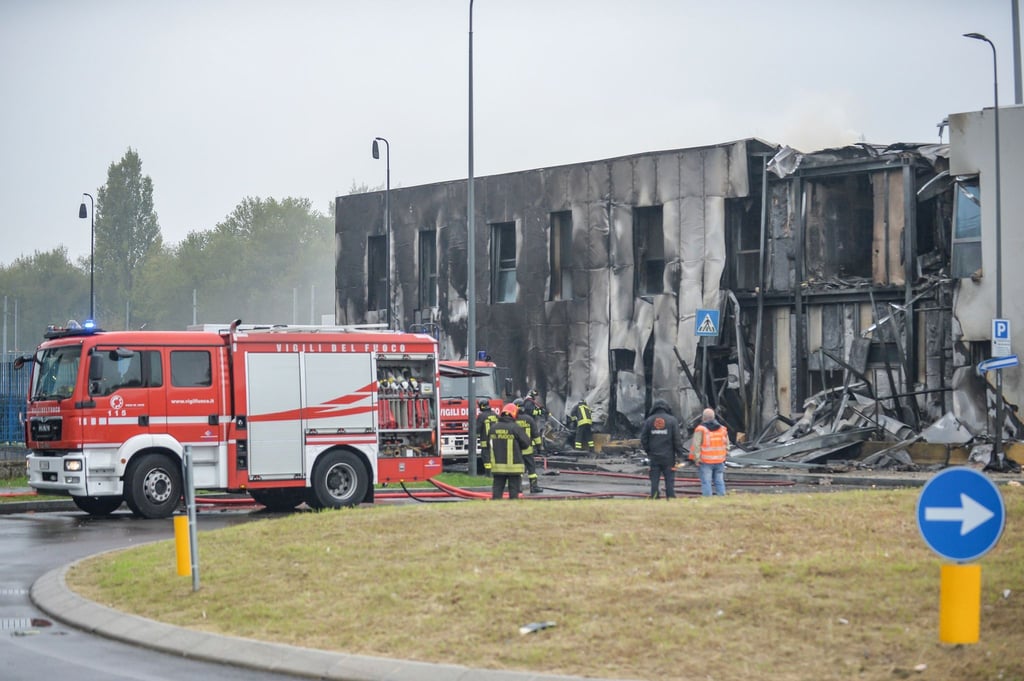 Feuerwehrleute stehen an der Unfallstelle, nachdem ein Leichtflugzeug kurz nach dem Start abgestützt und in ein leerstehendes Bürogebäude gekracht ist.