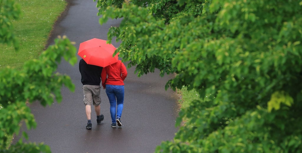 Mit einem Regenschirm schützt sich ein Paar vor Niederschlag.