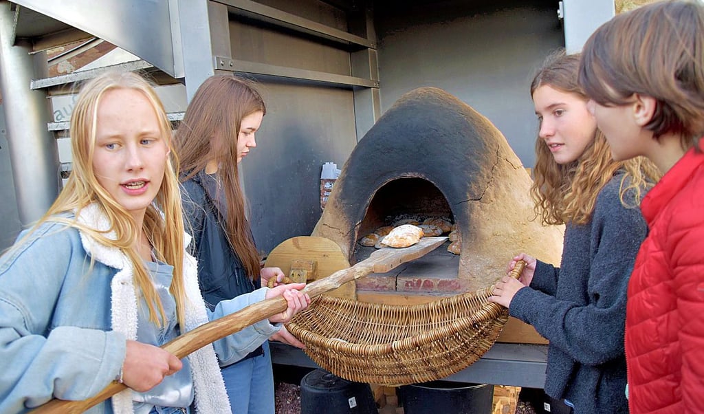 Raphaela, Anna, Merlind und Ginny (v.l.) holen Brot aus dem Lehmbackofen.