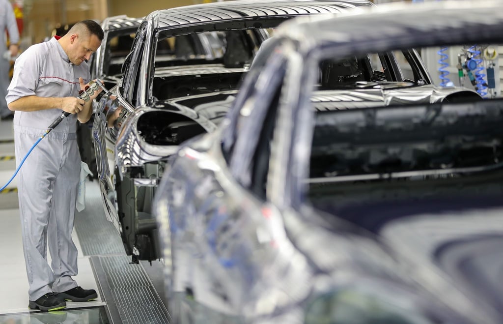 Ein Mitarbeiter poliert den Lack einer Karosse eines Porsche Macan in der Lackiererei im Werk Leipzig.