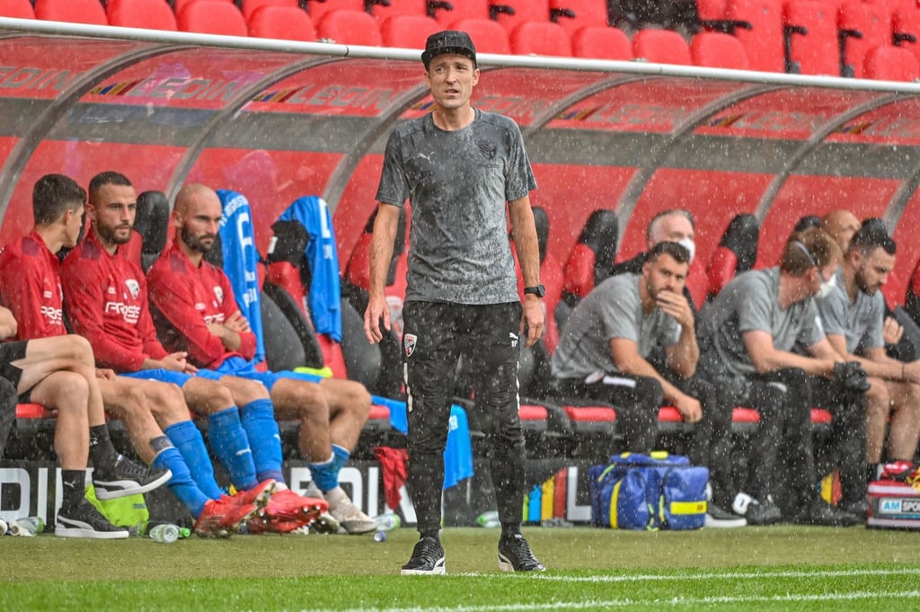 Trainer Roberto Pätzold steht am Spielfeldrand im Regen.
