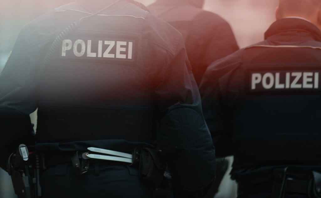 Polizisten stehen hinter einem Absperrband.