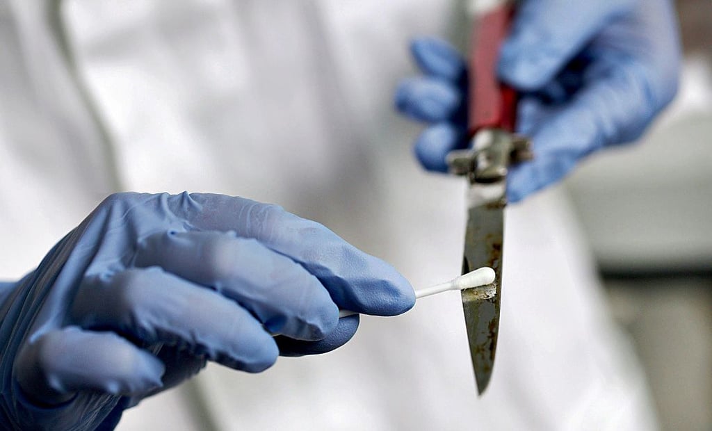 Ein Kriminalist sichert an einem Tatmesser Blut.