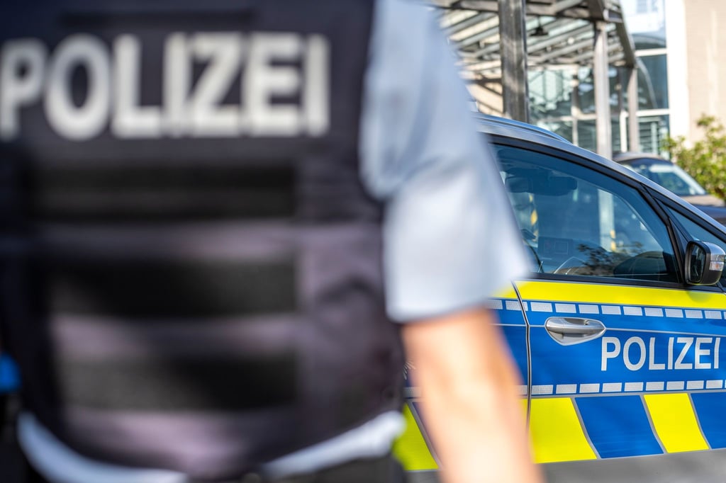 Ein Polizist steht vor einem Streifenwagen.