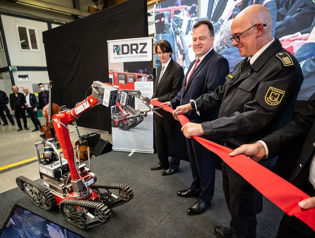 Ein Roboter schneidet zur Eröffnung des „Living Lab“ des Deutschen Rettungsrobotik Zentrums ein rotes Band durch.