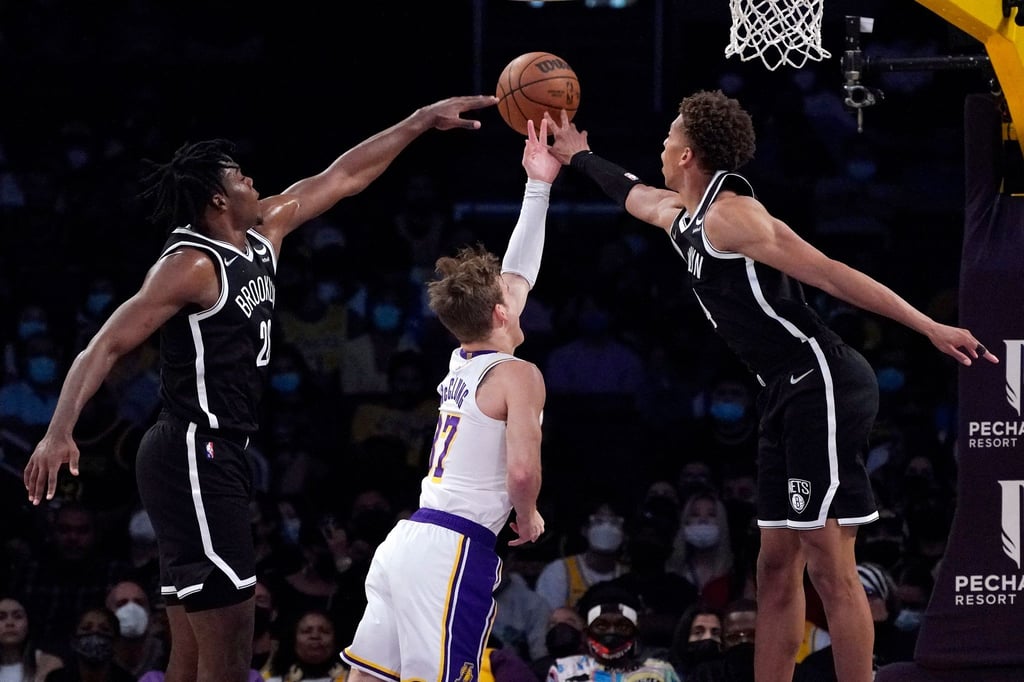 Day'Ron Sharpe (l) und Kessler Edwards (r) von den Brooklyn Nets verteidigen am Korb gegen Los Angeles Lakers-Guard Mac McClung.