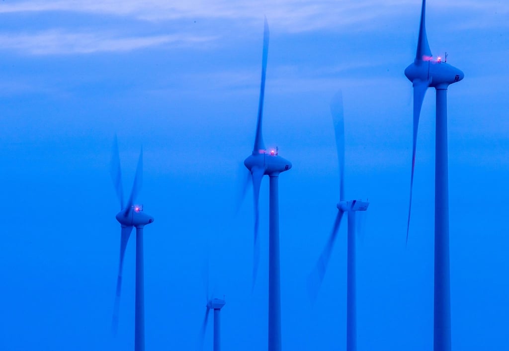 Windkraftanlagen drehen sich vor Sonnenaufgang in einem Windpark bei Kladrum.