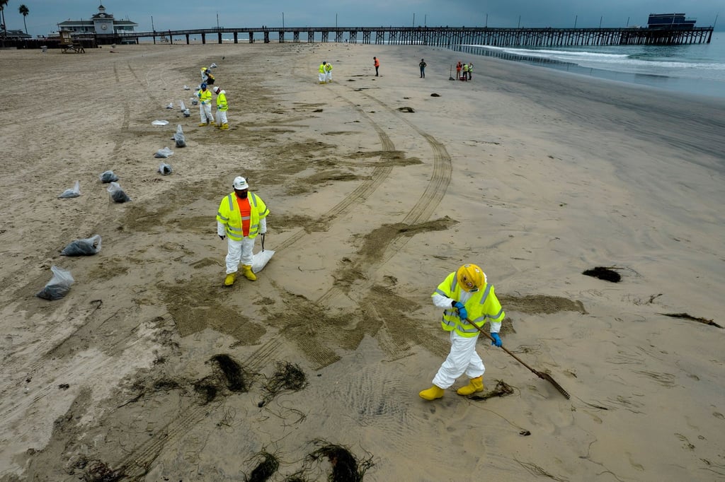 Arbeiter in Schutzanzügen reinigen den Strand nach einem Ölaustritt in Newport Beach, Kalifornien.