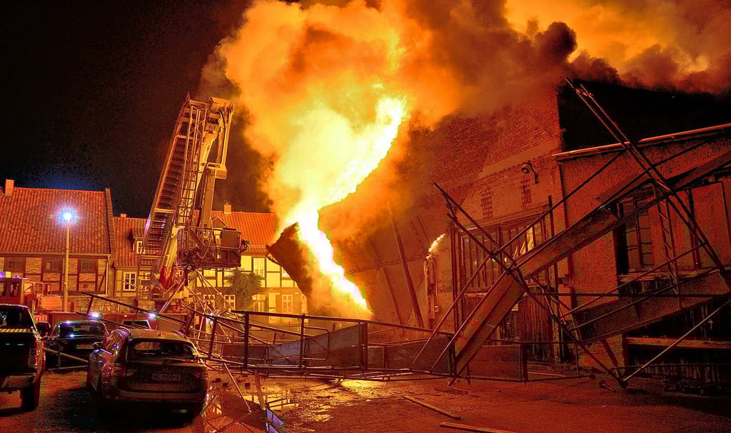 Bei der Verpuffung in Quedlinburg wurde eine Hallenwand aufgerissen, die wiederum eine Baugerüst umwarf. Anschließend waren sowohl das Hubbühnenfahrzeug als auch der darauf sitzende Feuerwehrmann der Gluthitze direkt ausgesetzt.