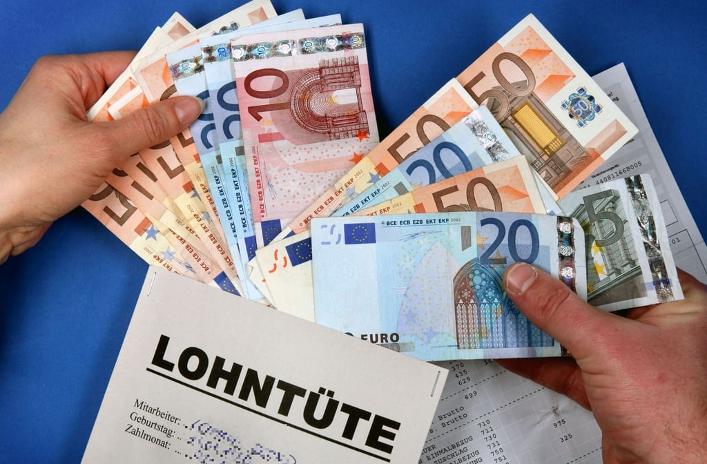 Illustration: Hände stecken Euro-Geldscheine in eine Lohntüte.
