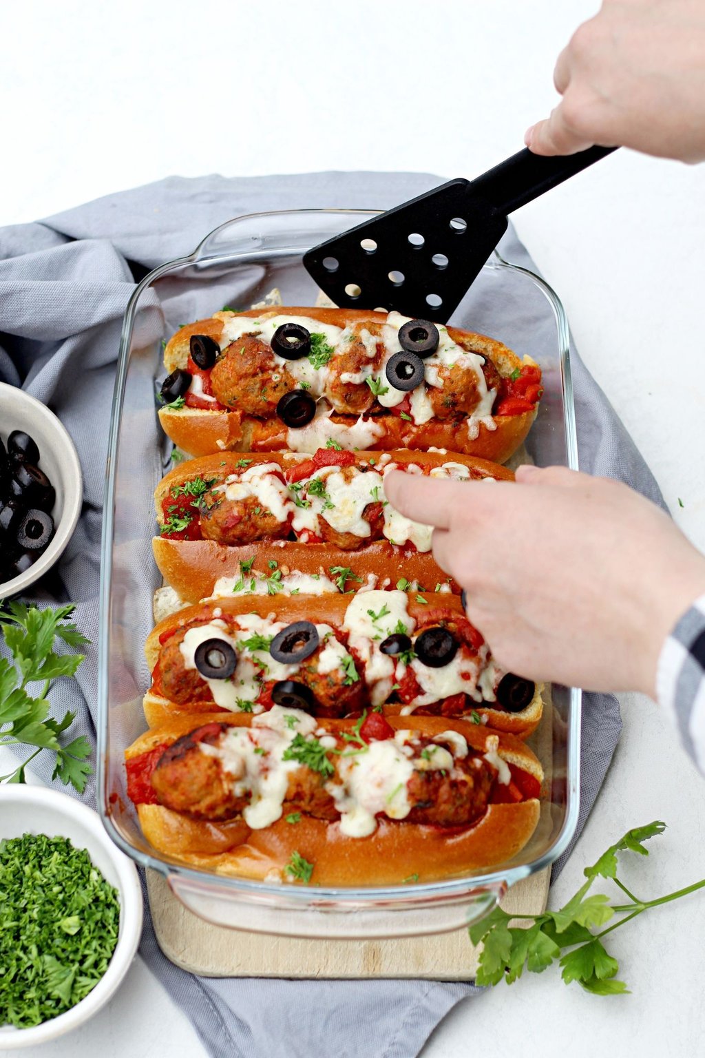 Bevor die Meatball Sandwiches im Ofen für 10 Minuten mit Mozzarella überbacken werden, kommen in jedes Briochebrötchen 3 Hackbällchen und etwas Soße.