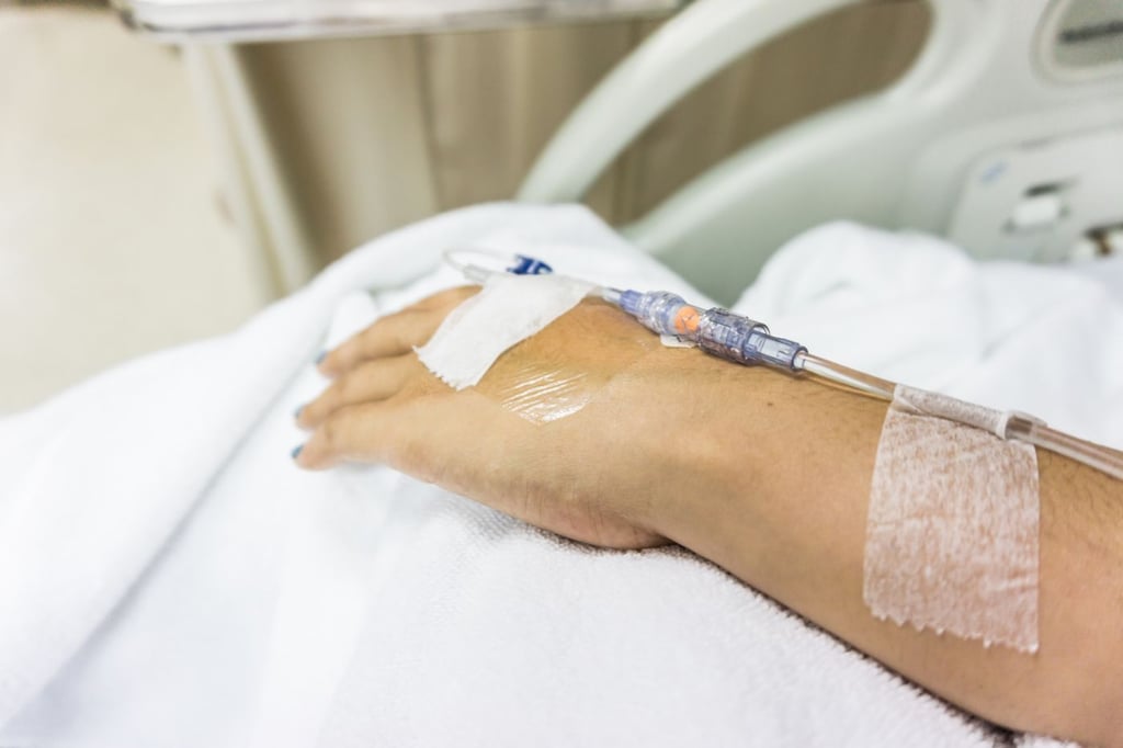 Illustration: Ein Schlauch ist intravenös an die Hand eines Patienten angeschlossen.