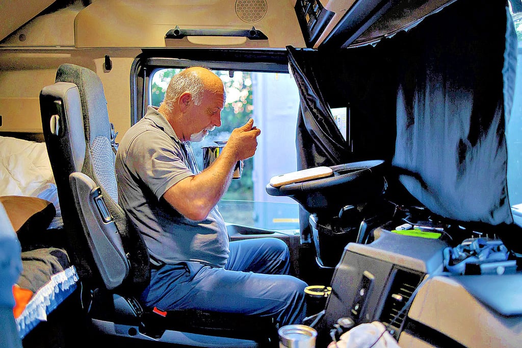 Ein Trucker isst am Abend auf einem Autobahnparkplatz eine Tütensuppe, bevor er sich schlafen legt.
